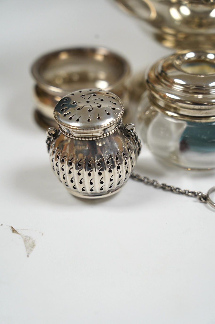 An Edwardian silver boat shaped sugar basket, by Thomas Bradbury & Sons, London, 1905, 13.9cm, together with two silver napkin rings, mounted glass hair tidy and a sterling pomander. Condition - poor to fair